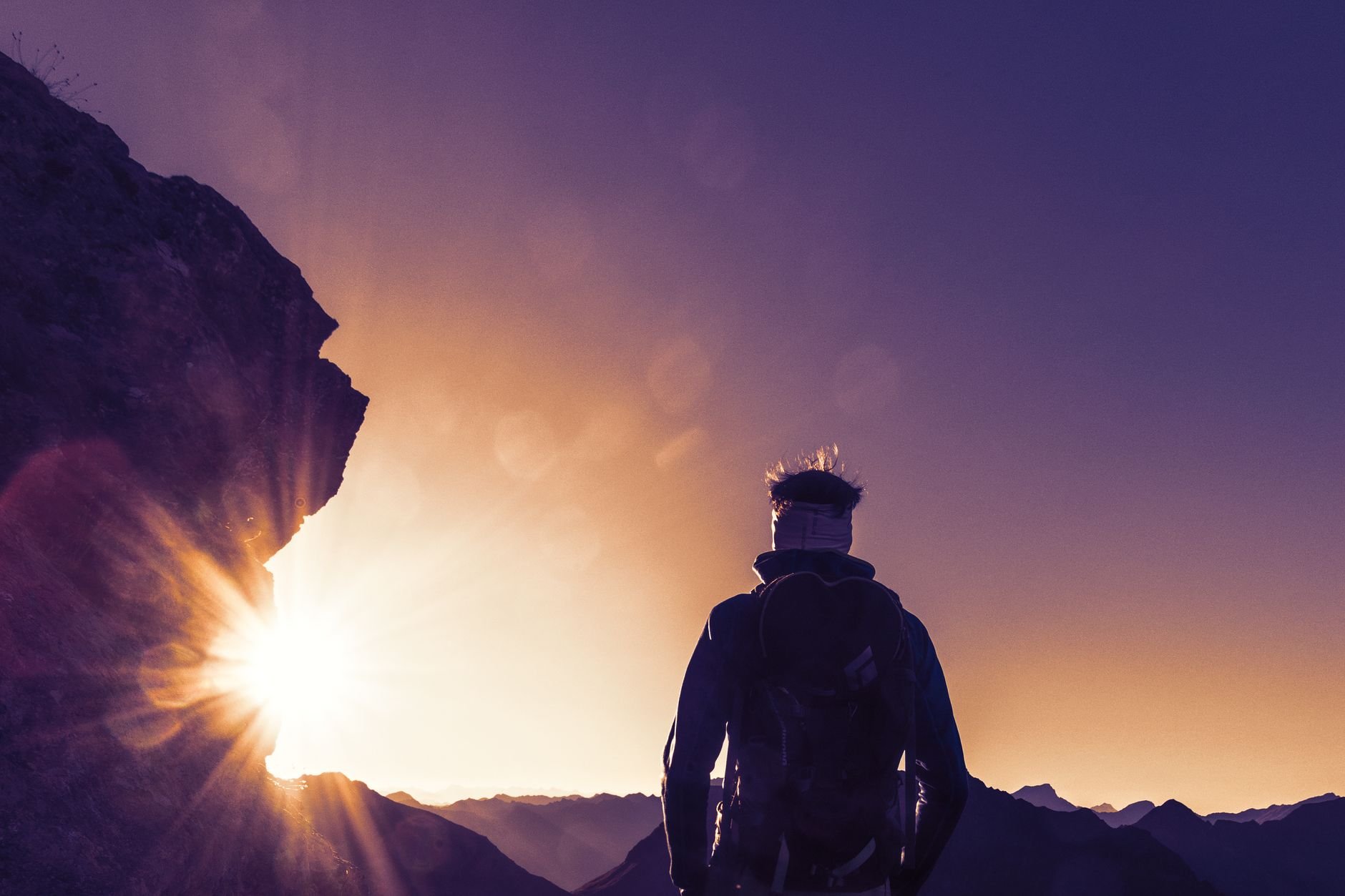 Silhouette of a hiker climbing a mountain trail at sunrise, representing freedom and new horizons