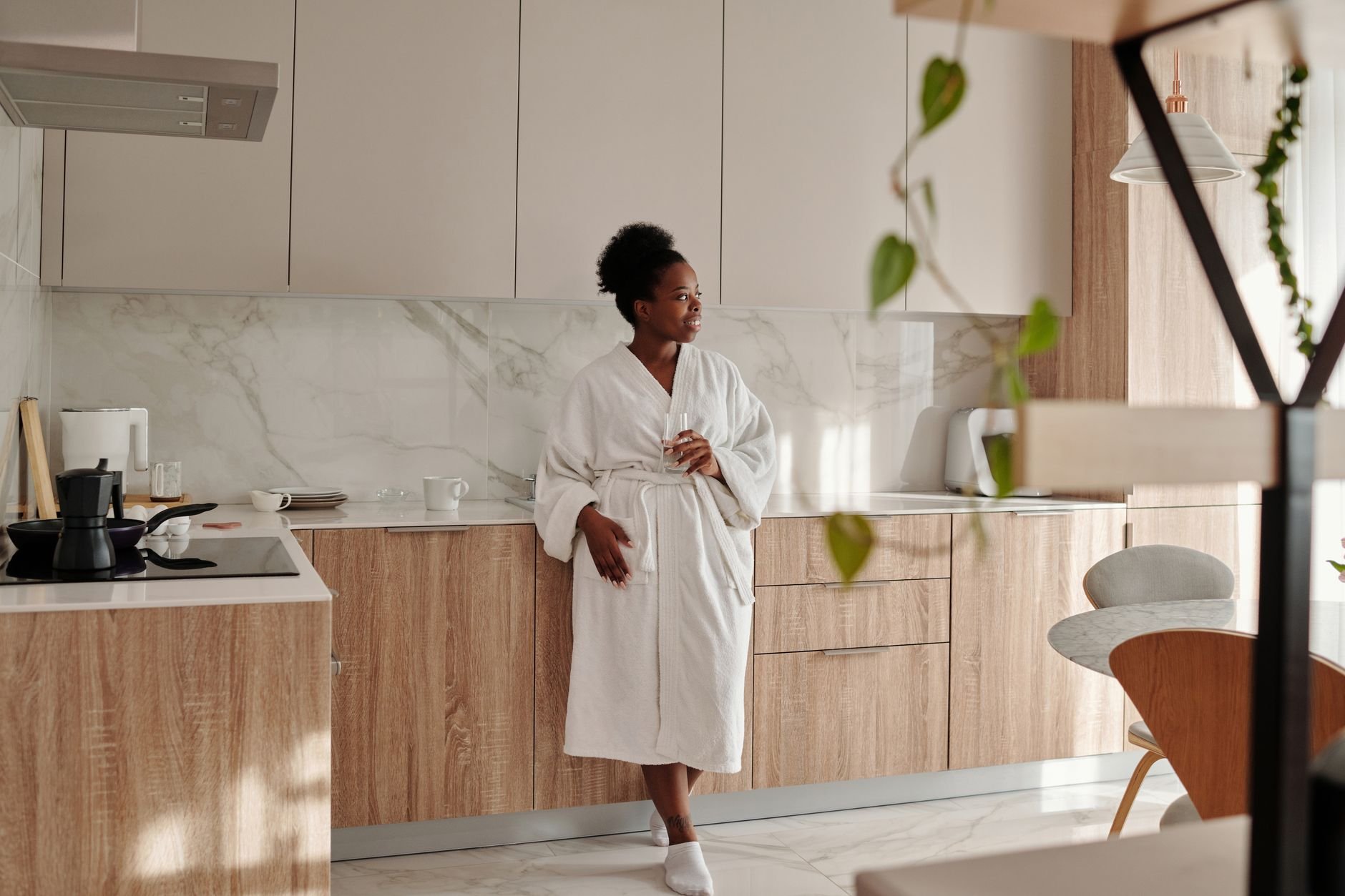 Woman enjoying morning wellness ritual, drinking water in golden light